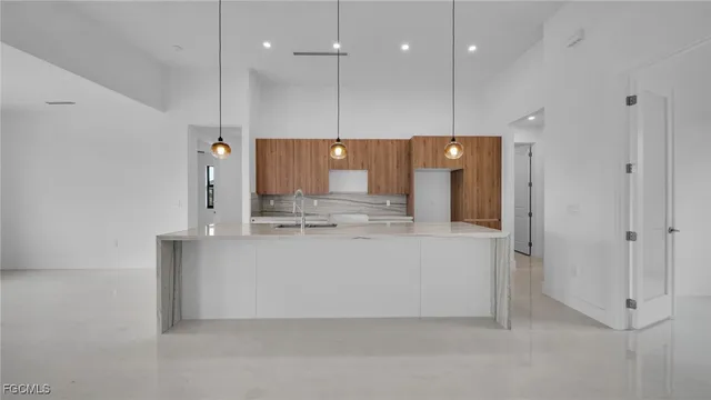 a large white kitchen with a large refrigerator a sink and a fireplace