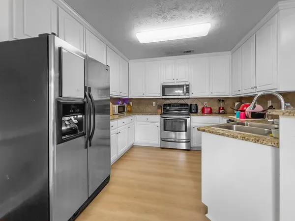a kitchen with stainless steel appliances granite countertop a refrigerator sink and stove