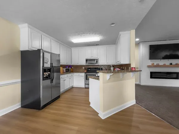 a kitchen with stainless steel appliances granite countertop a refrigerator a stove a sink and a microwave