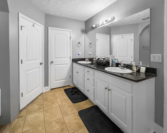 a spacious bathroom with a double vanity sink a mirror and a