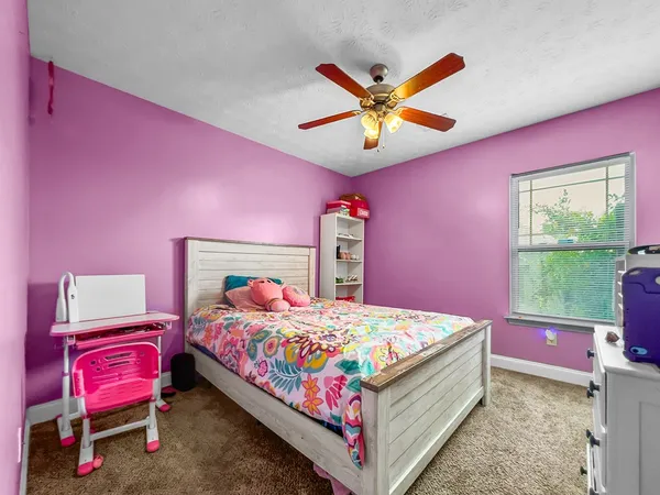 a bedroom with a bed a chandelier and pink walls