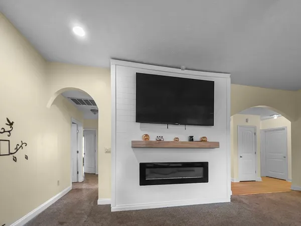 a living room with flat screen tv and a ceiling fan