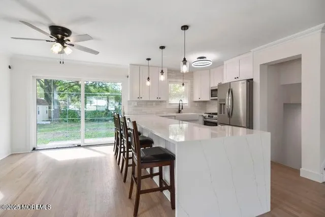 a kitchen with kitchen island stainless steel appliances a table chairs refrigerator and sink
