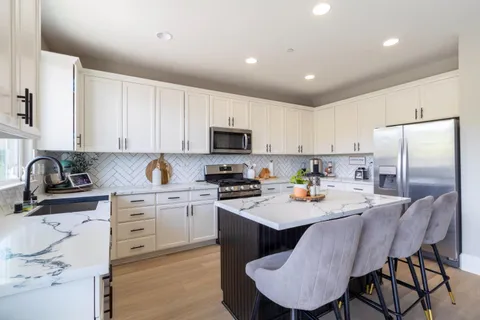 a kitchen with stainless steel appliances granite countertop a stove a sink a refrigerator a microwave and cabinets