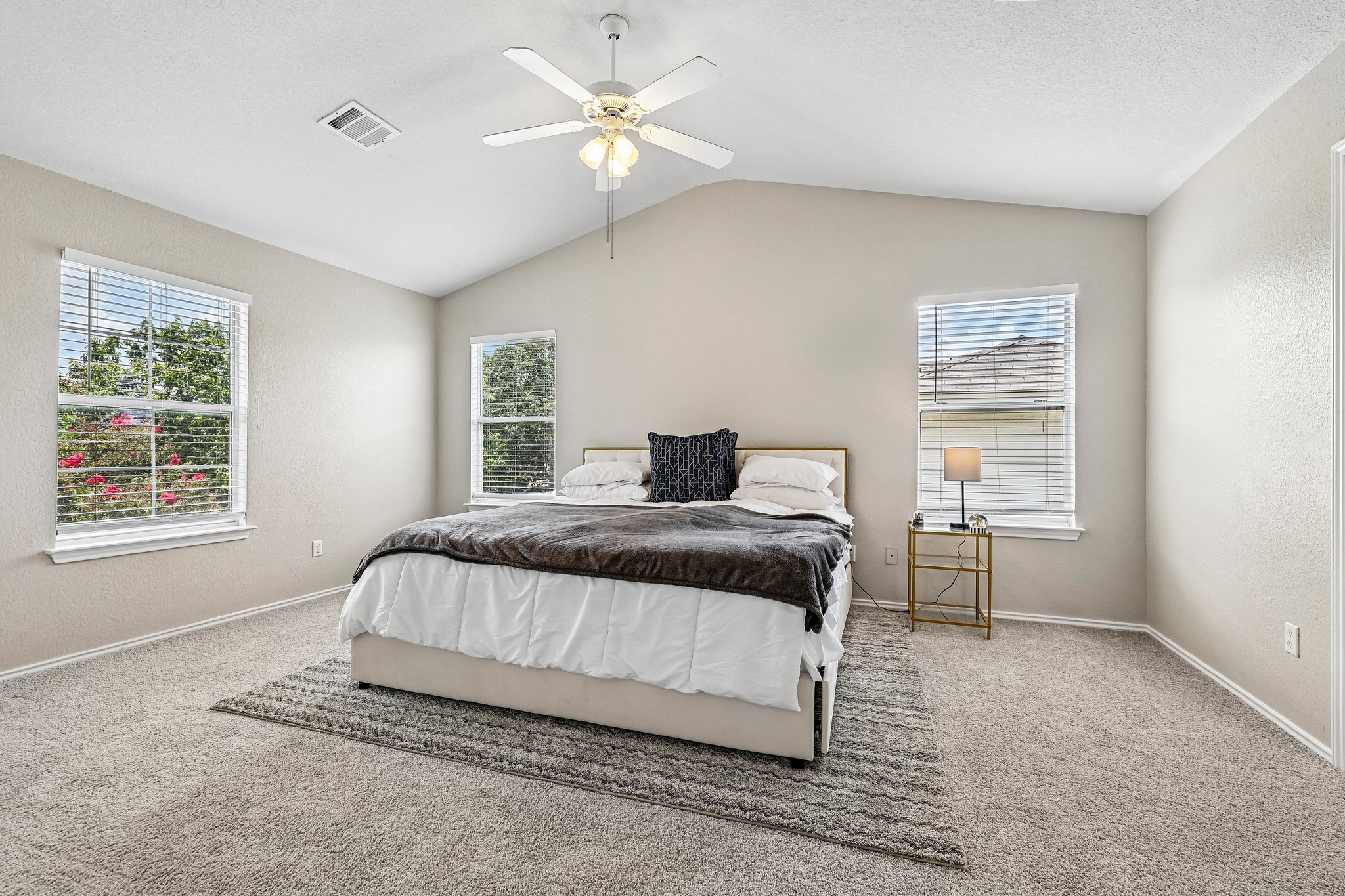 616 Scheel Road Kyle, TX 78640 - Photo 21 of 39 A spacious bedroom features vaulted ceilings, inviting carpeted floors, and multiple sun-filled windows.