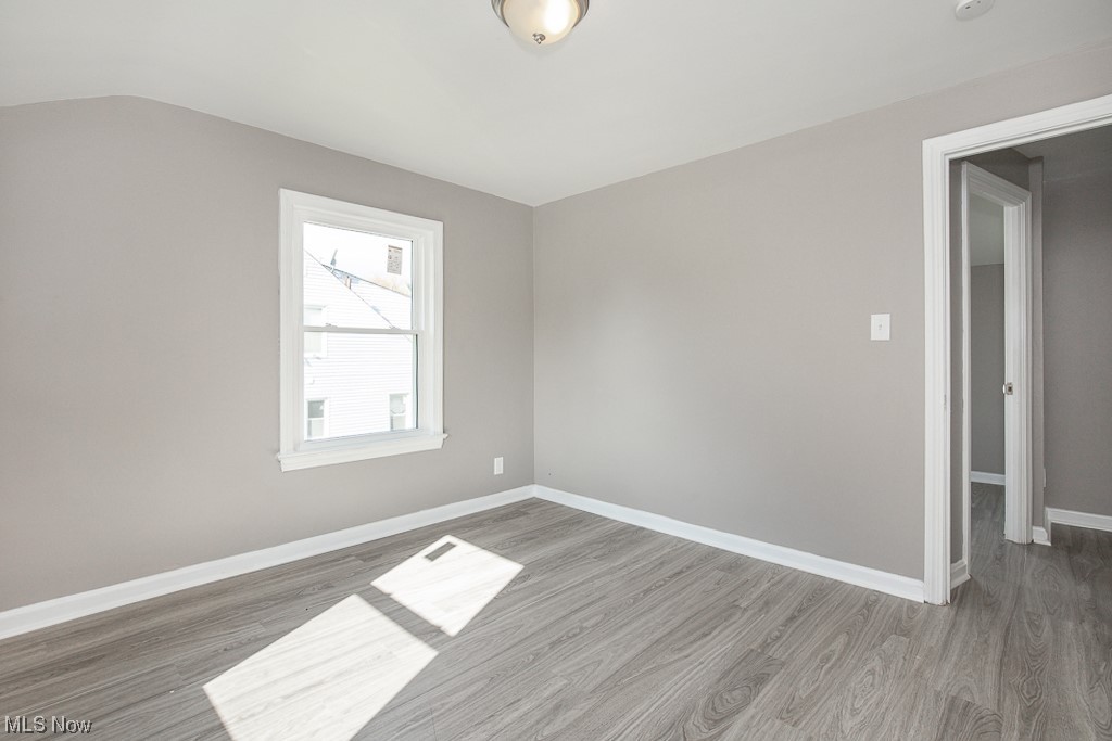 19109 Libby Road Maple Heights, OH 44137 - Photo 13 of 32 Empty room with vaulted ceiling and wood-type flooring