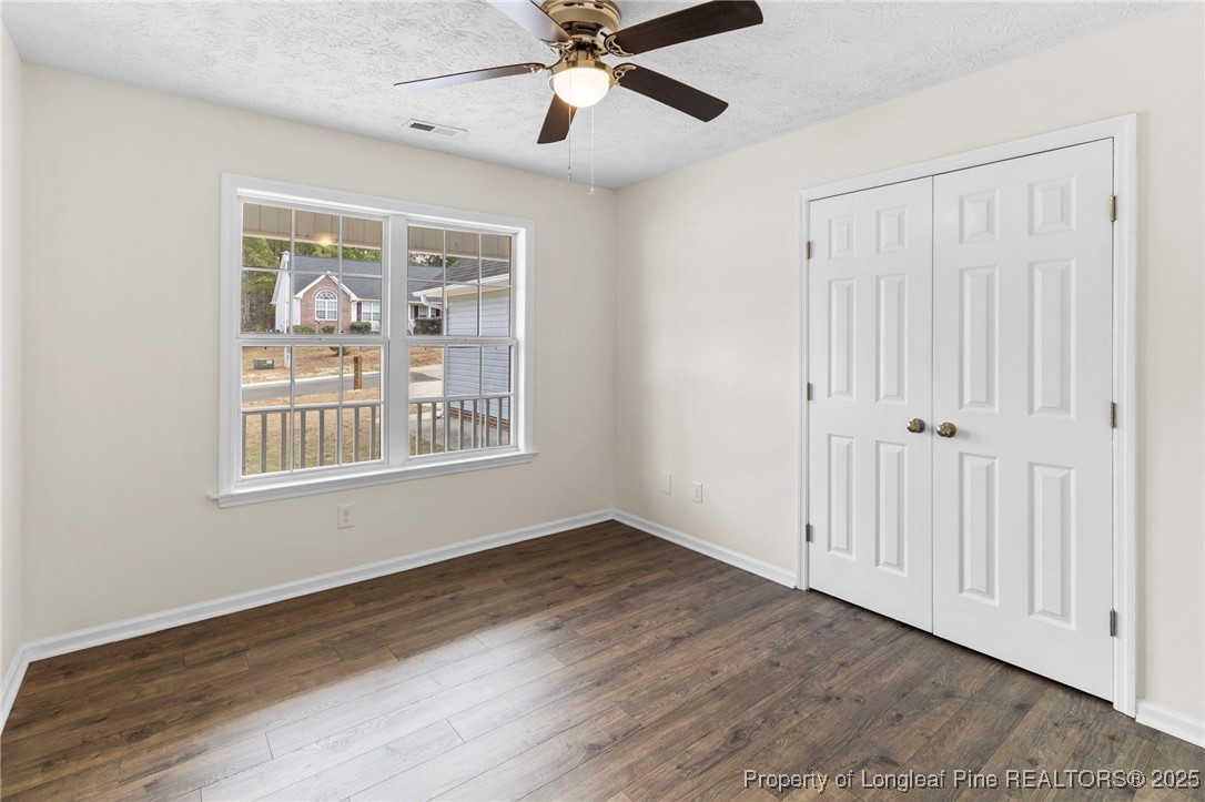 5520 Rising Ridge Drive Hope Mills, NC 28348 - Photo 15 of 30 an empty room with wooden floor chandelier fan and windows