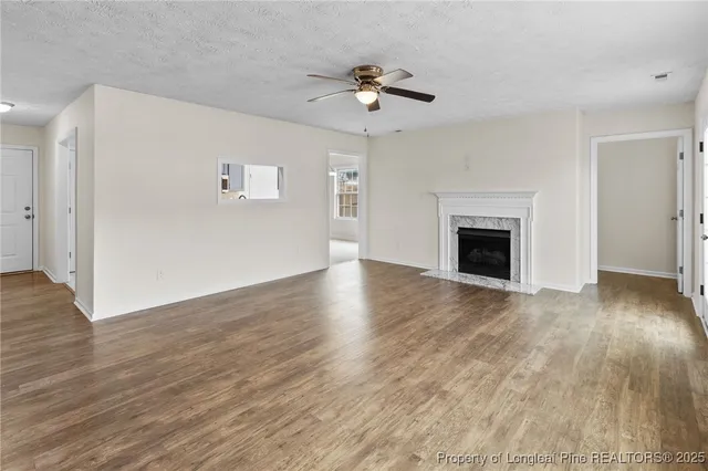 a view of an empty room with wooden floor fireplace and a window