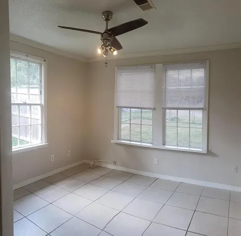 an empty room with chandelier fan and windows