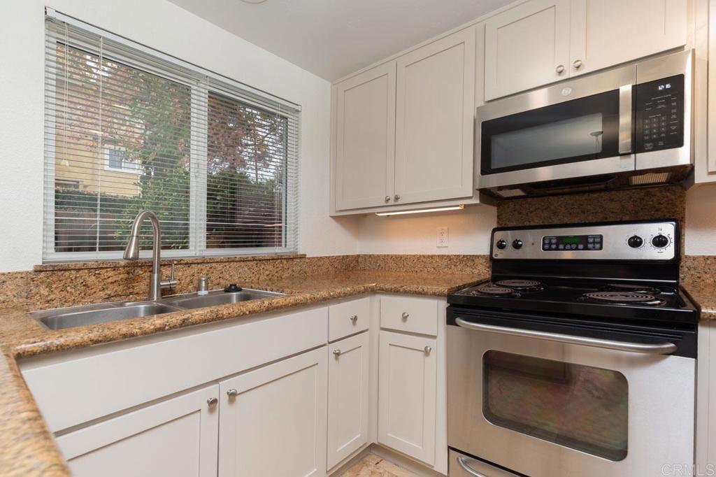505 San Pasqual Valley Road, Unit 186 Escondido, CA 92025 - Photo 6 of 28 a kitchen with granite countertop a stove a microwave and sink