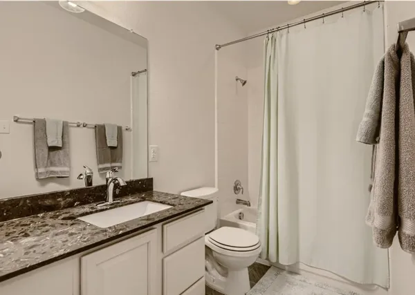 a bathroom with a granite countertop sink toilet and shower