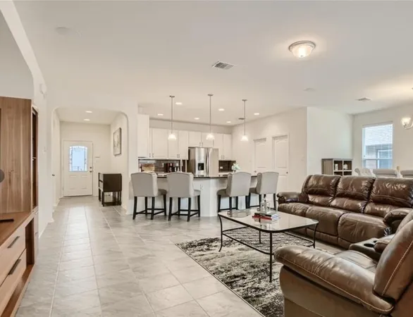 a living room with furniture kitchen view and a large window