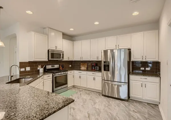 a kitchen with stainless steel appliances granite countertop a refrigerator stove microwave and sink