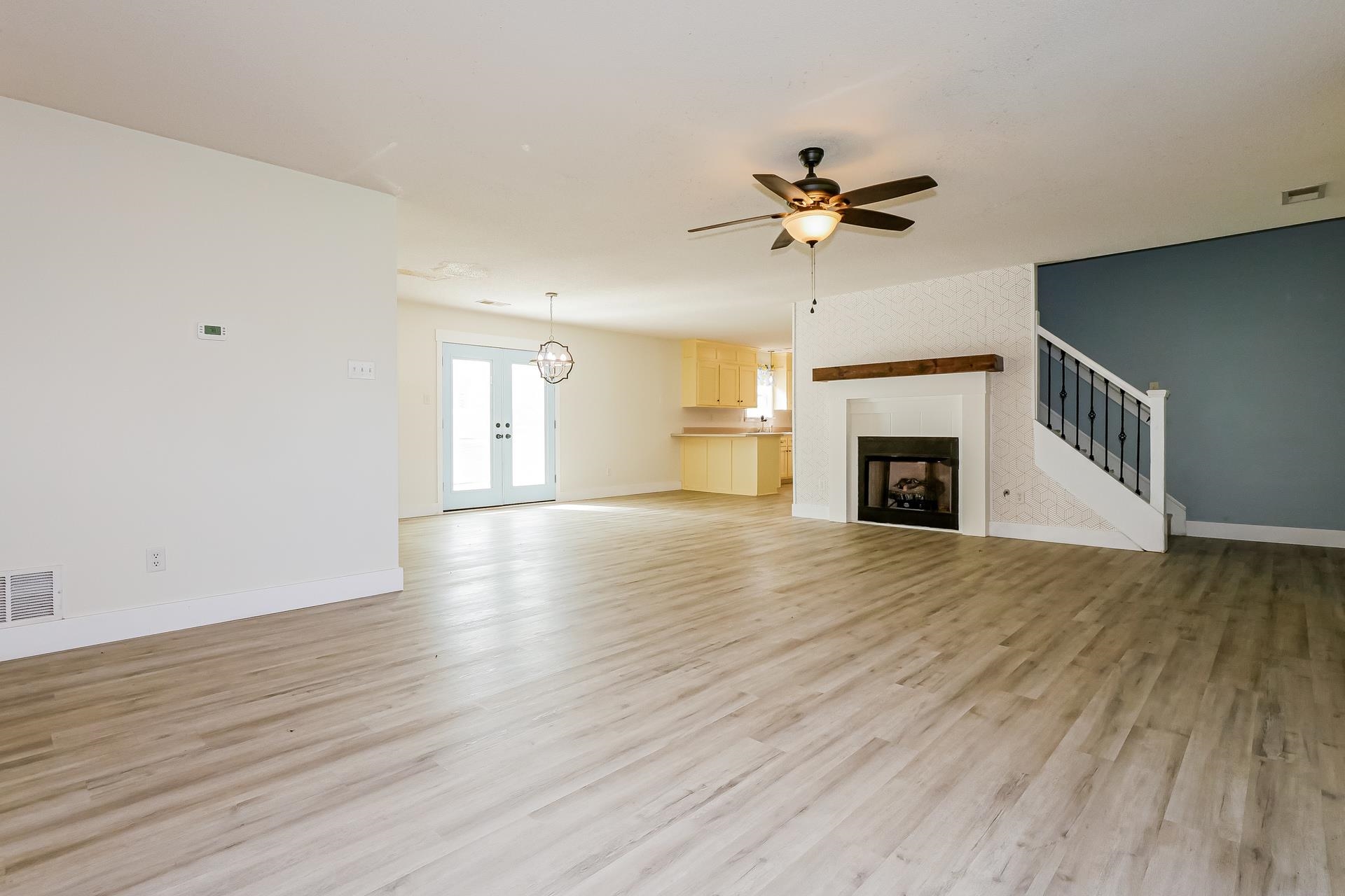 188 David Reed Drive Munford, TN 38058 - Photo 3 of 20 Spacious living area featuring light wood-finish flooring, a white fireplace with a dark wood mantel, and a ceiling fan with integrated lighting
