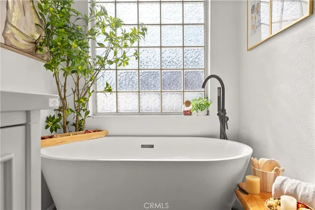 a white bath tub sitting in a bathroom next to a window
