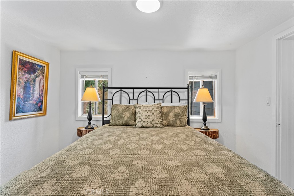 1139 Bear Springs Road Twin Peaks, CA 92391 - Photo 21 of 45 a spacious bedroom with a bed and a painting on the wall