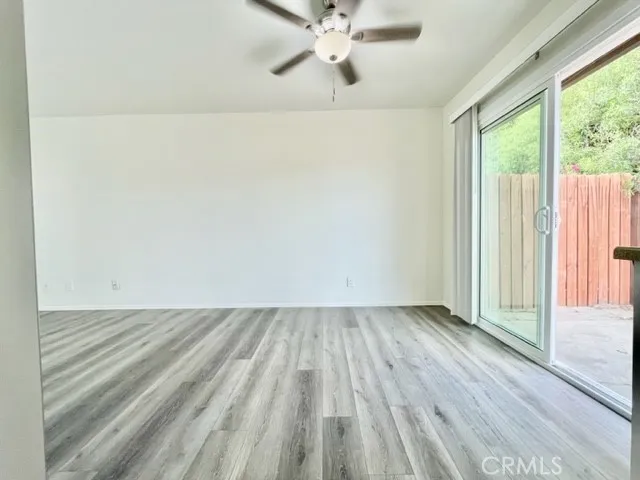 an empty room with wooden floor fan and windows