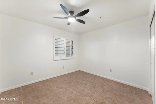 an empty room with ceiling fan and windows