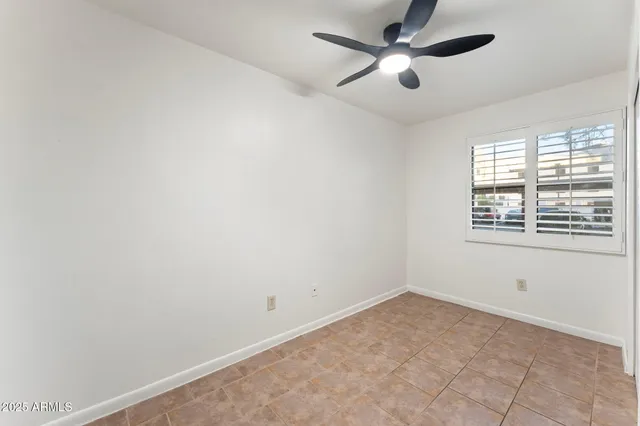 an empty room with a window and a fan