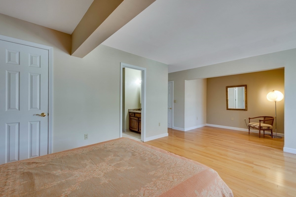 75 Page Road, Unit 16 Bedford, MA 01730 - Photo 14 of 27 a bedroom with a bed and a lamp on dresser with wooden floor