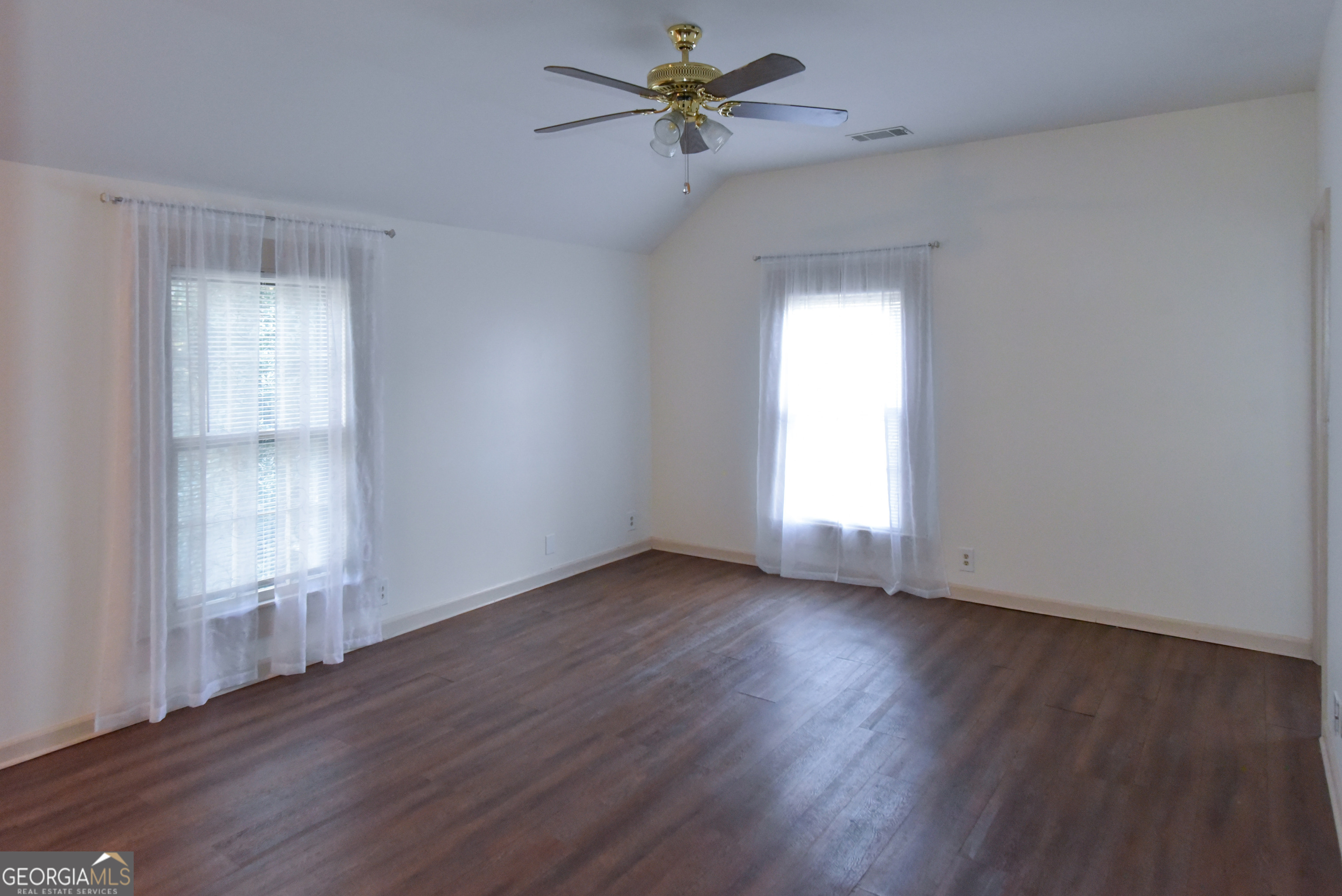 302 Jefferson Street, Unit B Springfield, GA 31329 - Photo 10 of 24 an empty room with wooden floor chandelier fan and windows