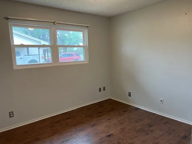 a view of an empty room with wooden floor and closet