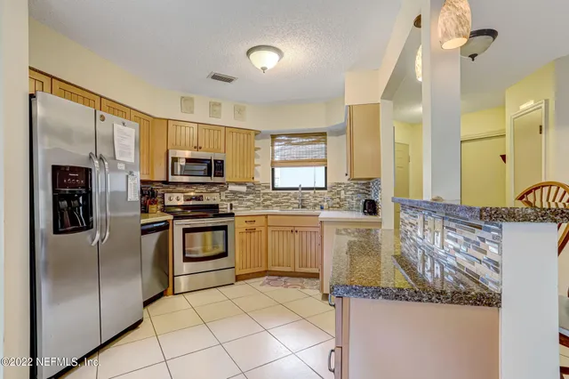 a kitchen with stainless steel appliances granite countertop a refrigerator a stove and a sink