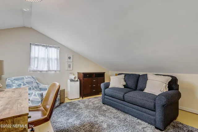a living room with furniture and a dining table with rug