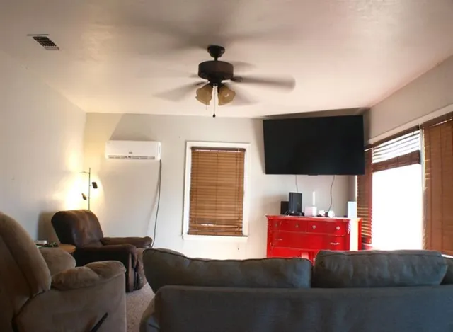 a living room with furniture a flat screen tv and a window
