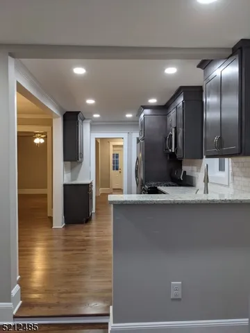a view of kitchen with stainless steel appliances wooden floor and living room