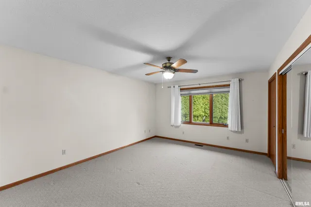 an empty room with windows and chandelier fan