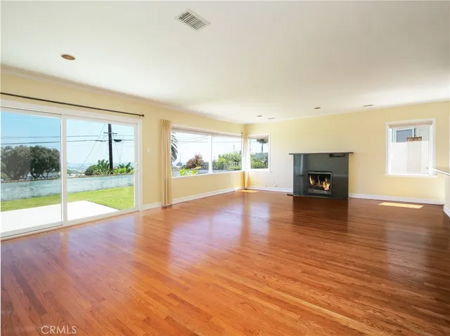 a view of empty room with wooden floor and fireplace
