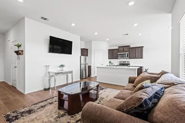 a living room with furniture kitchen view and a flat screen tv