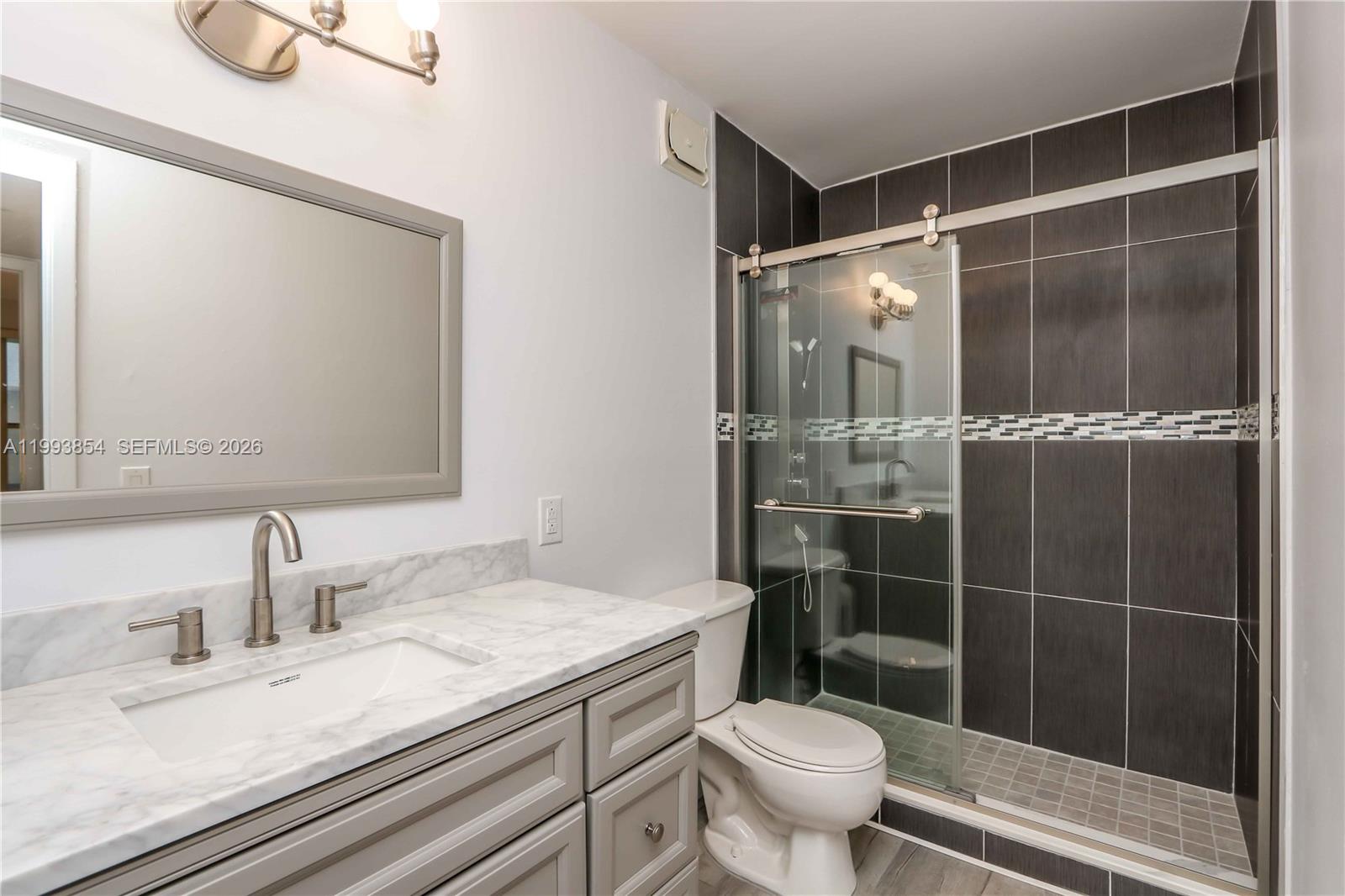 13785 Southwest 66th Street, Unit 239C Miami, FL 33183 - Photo 12 of 17 a bathroom with a granite countertop sink toilet and shower