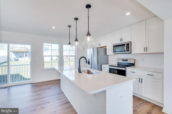 a kitchen with stainless steel appliances kitchen island granite countertop a refrigerator a sink and white cabinets