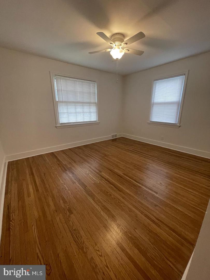 105 Breslin Avenue Haddonfield, NJ 08033 - Photo 7 of 15 a view of an empty room with chandelier fan and wooden floor