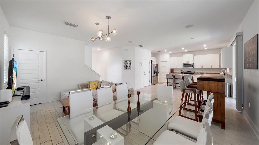 2587 Temple Street Sarasota, FL 34239 - Photo 11 of 54 a very nice looking open dining room with kitchen island stainless steel appliances refrigerator stove a sink dishwasher a dining table and chairs with wooden floor