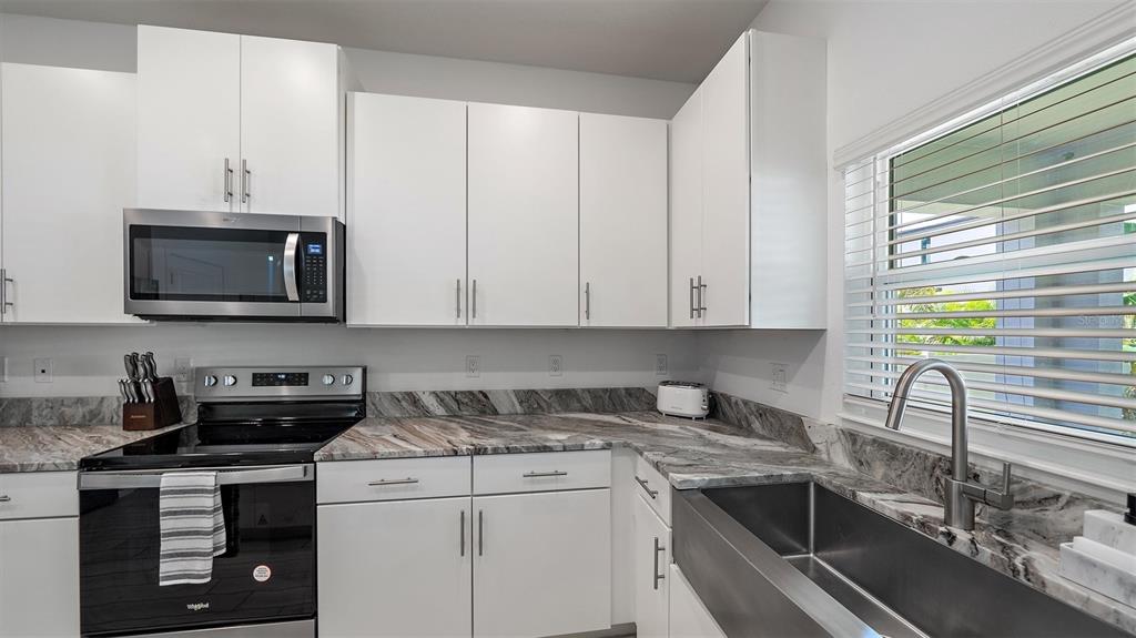 2587 Temple Street Sarasota, FL 34239 - Photo 12 of 54 a kitchen with stainless steel appliances granite countertop a sink a stove and a microwave