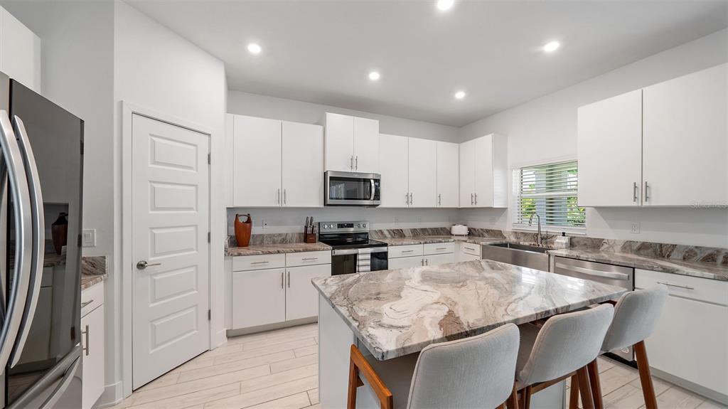 2587 Temple Street Sarasota, FL 34239 - Photo 7 of 54 a kitchen with stainless steel appliances granite countertop a stove a sink a refrigerator white cabinets and a refrigerator