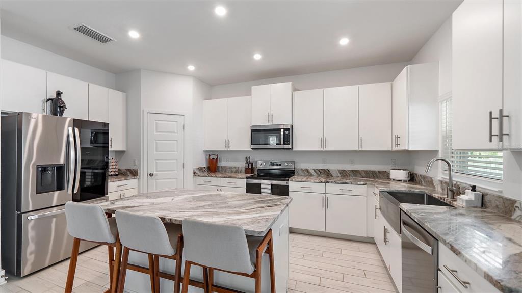 2587 Temple Street Sarasota, FL 34239 - Photo 10 of 54 a kitchen with stainless steel appliances granite countertop a stove top oven a refrigerator a sink and chairs