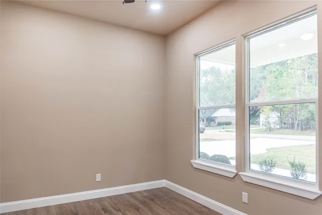 a view of an empty room with wooden floor and window
