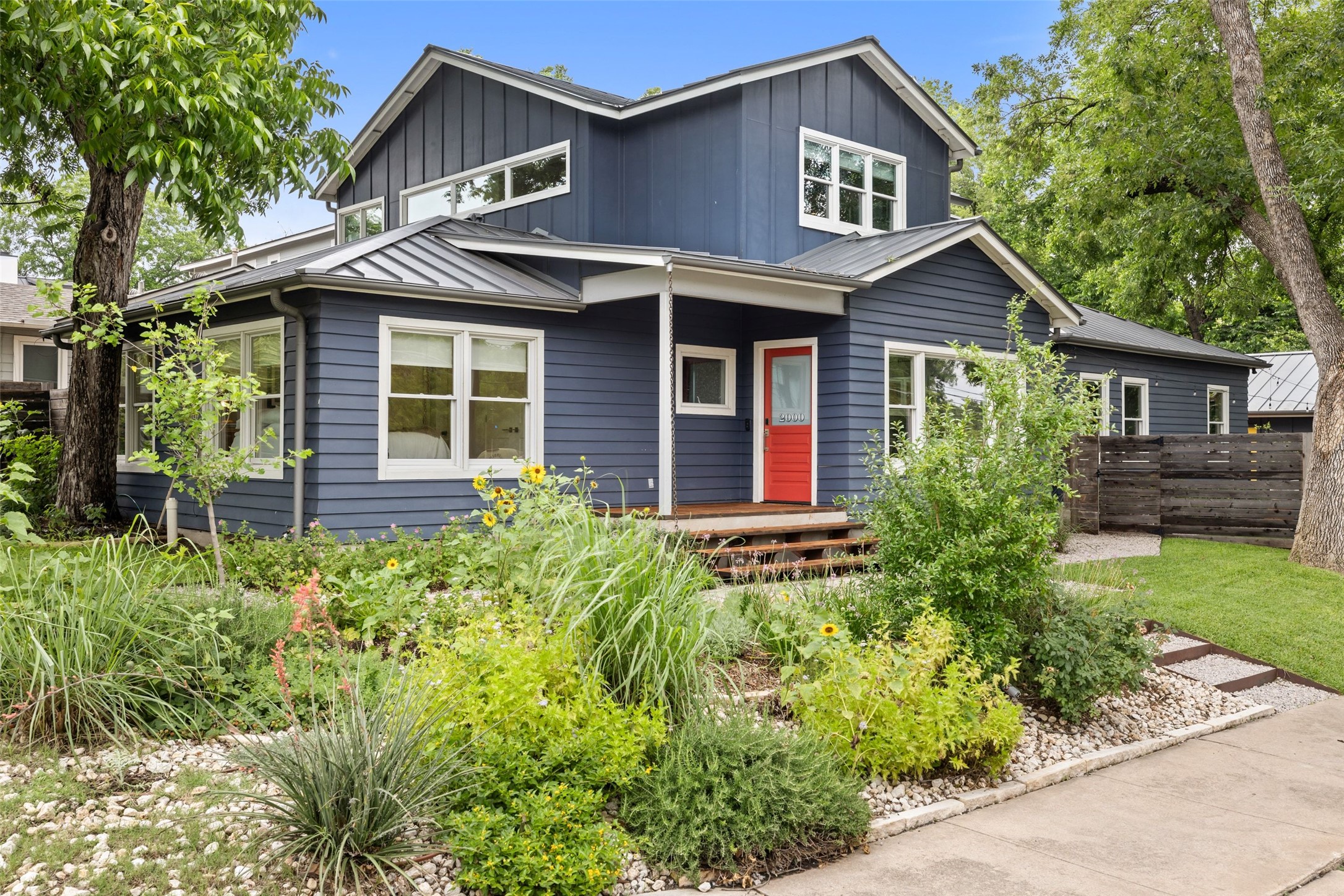 2000 Rundell Place Austin, TX 78704 - Photo 4 of 38 A well-maintained facade features a striking red door and mature landscaping.