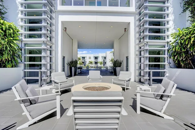 a living room with furniture a potted plant and a kitchen view