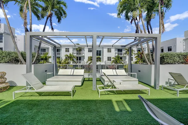 a view of a patio with a table and chairs under an umbrella with a barbeque grill and potted plants