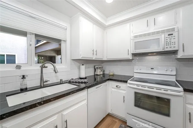 a kitchen with granite countertop white cabinets white stainless steel appliances and sink