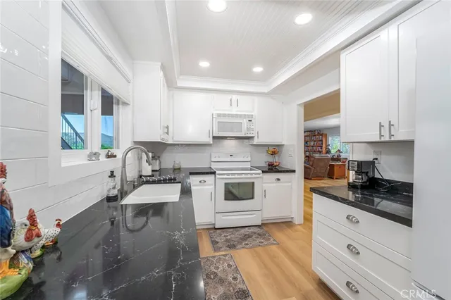 a kitchen with granite countertop white cabinets and white appliances