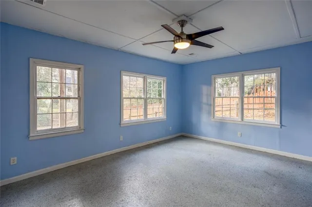 an empty room with windows and ceiling fan
