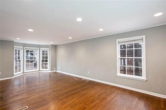 a view of an empty room with a window and wooden floor