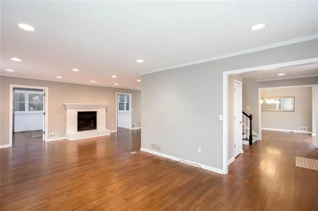 a view of an empty room with wooden floor and a fireplace