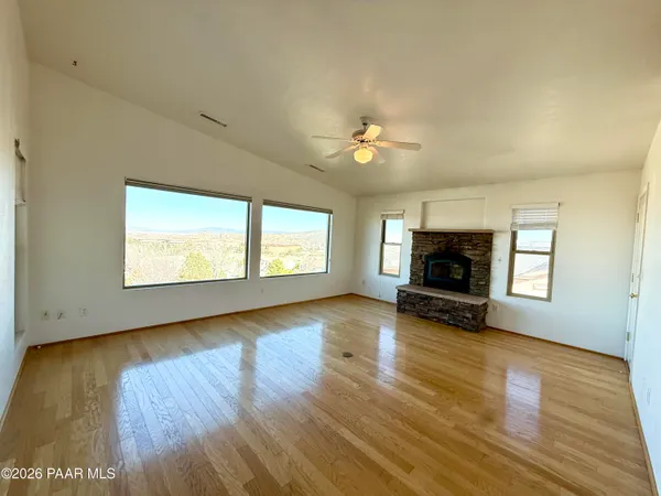 an empty room with windows fireplace and wooden floor